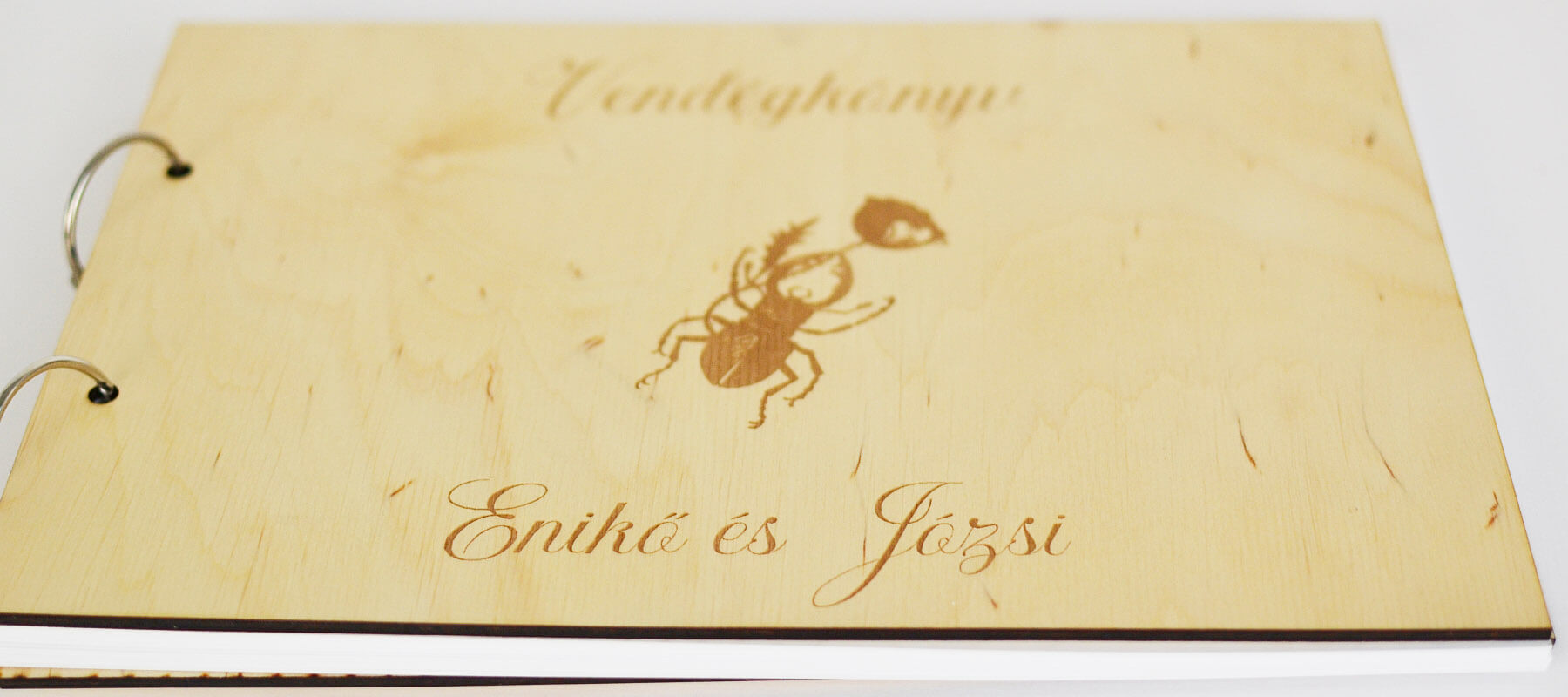 Az esküvői vendégkönyv fa szívek helyett virágot tartó bogárral